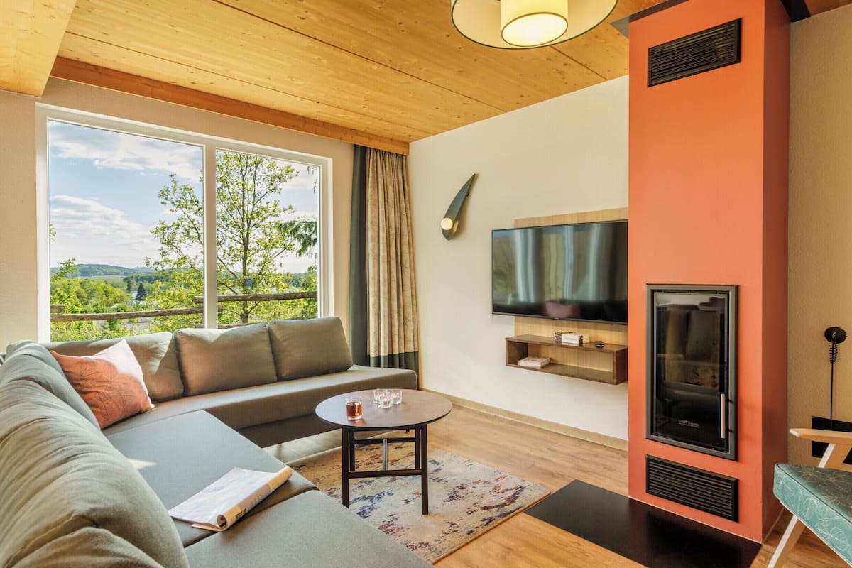 A modern living room with a sofa, a coffee table, a fireplace, and a TV mounted on the wall.