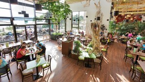 En rummelig restaurant med højt til loftet, store vinduer og indeplanter.