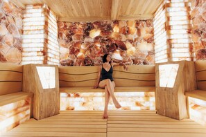 A wooden sauna with a stone wall and benches. - Center Parcs Le Bois aux Daims (Les-Trois-Moutiers)
