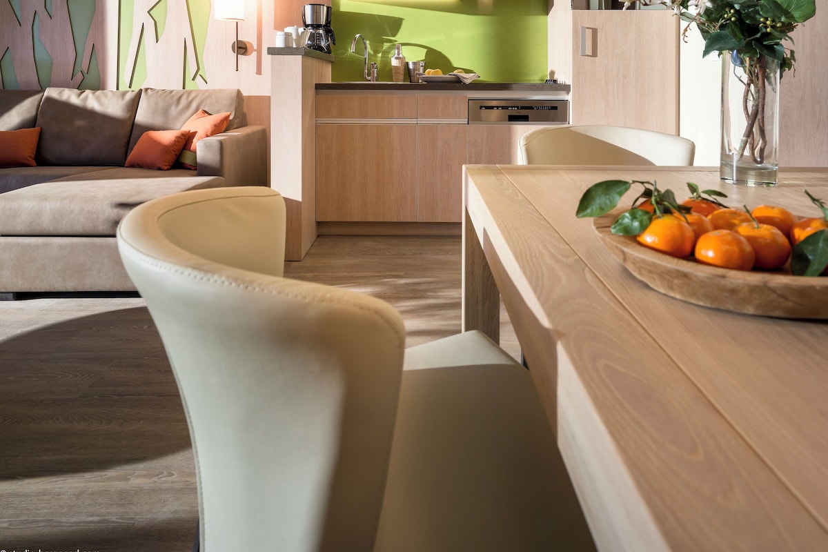 A modern kitchen with a green backsplash, wooden cabinets, and a coffee maker on the counter.