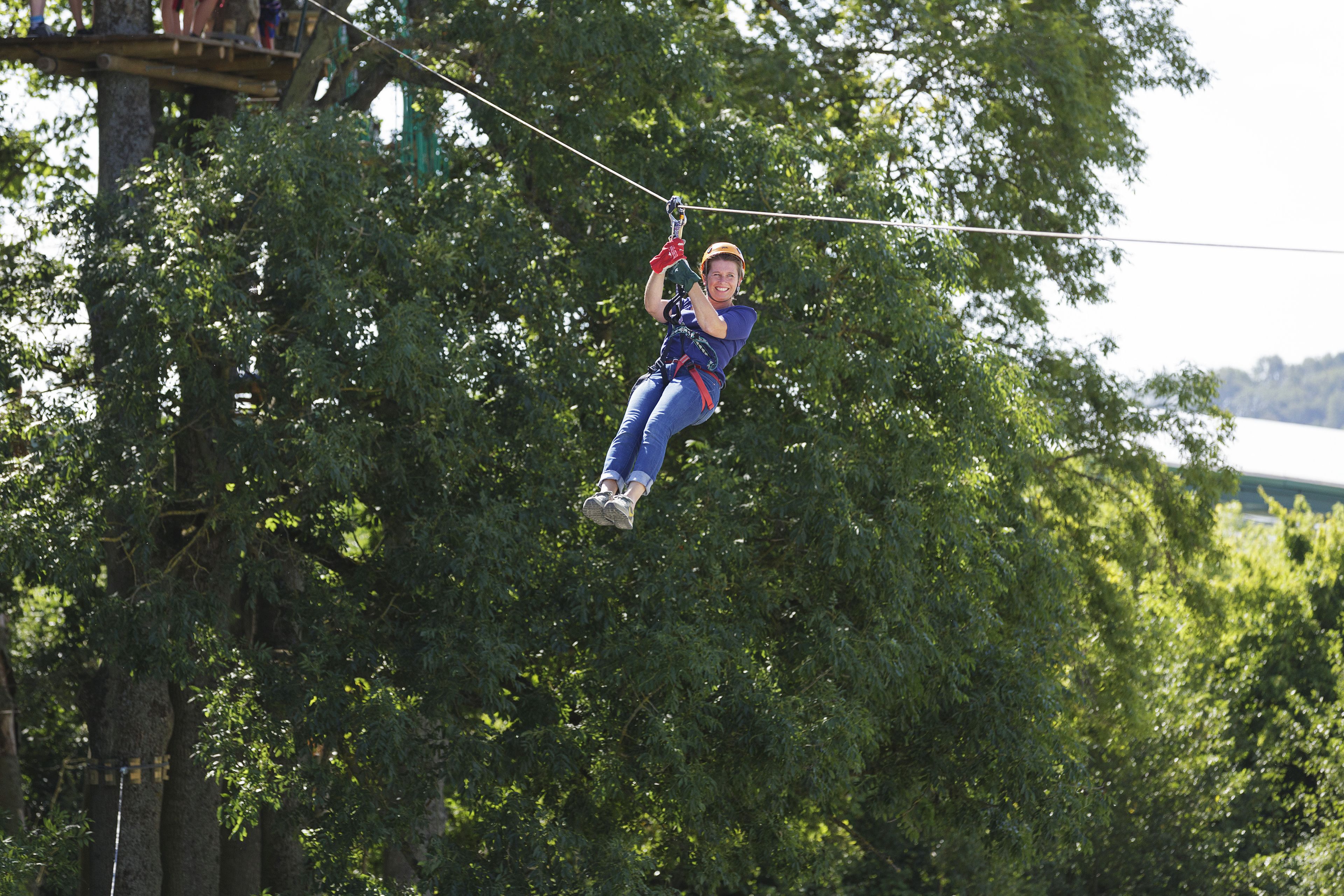A person zip-lining through a forested area.