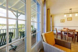 Enjoy a view of the deck from the large window, with a wicker chair and dining area inside.