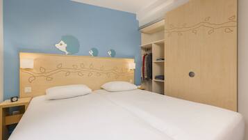 Ein Schlafzimmer mit einem großen Bett, einem Nachttisch, einem Kleiderschrank und einer Wand mit Blätermotiv.