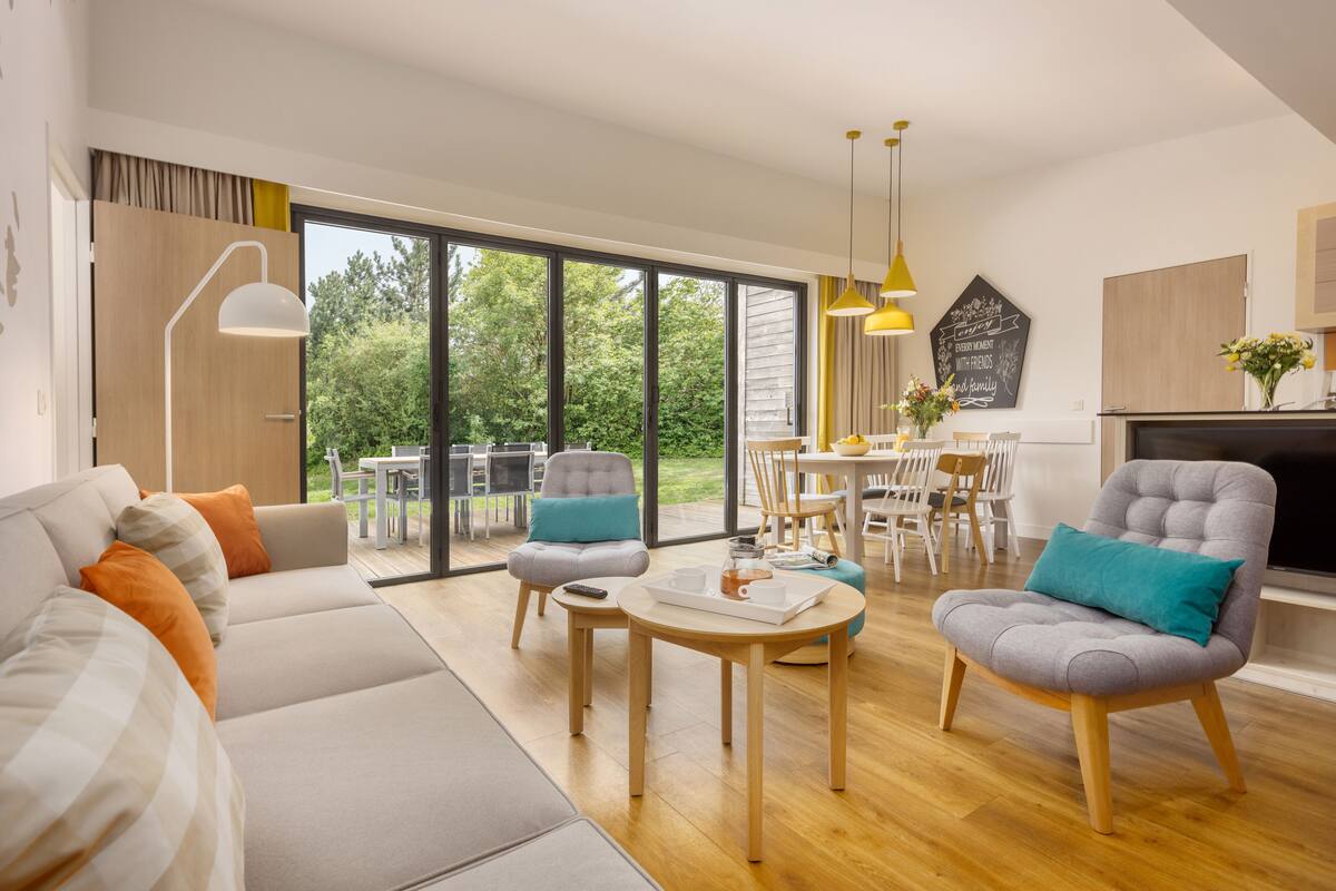 A spacious living room with a sofa, armchairs, a coffee table, and a dining area with chairs and a table.