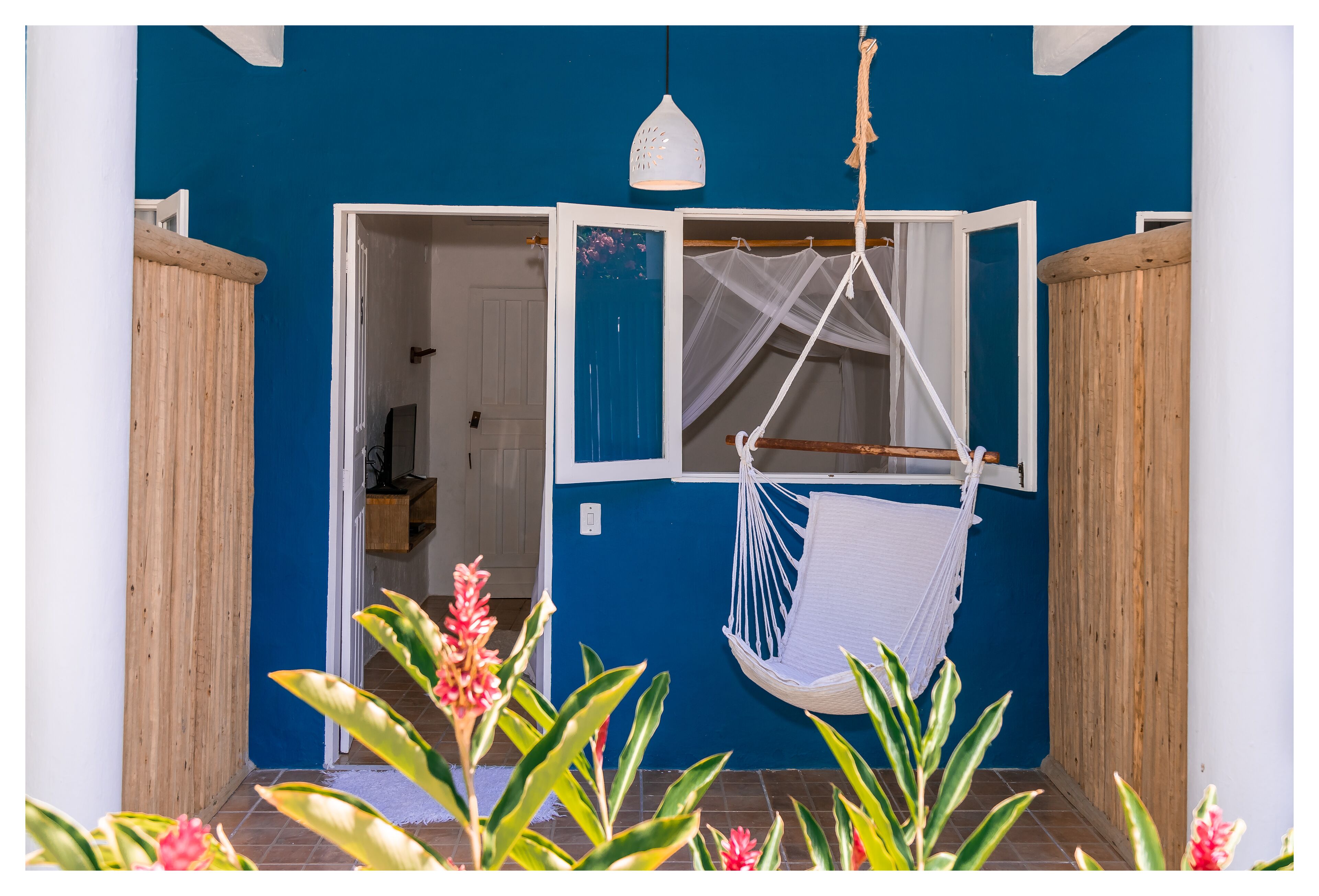 A blue-walled room with a white door, a hanging hammock, and a white pendant light.