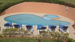 A swimming pool with a heart-shaped design, surrounded by white lounge chairs and a landscaped garden. - Beautiful 3 Bedroom ocean view villa in sosua (Sosúa)