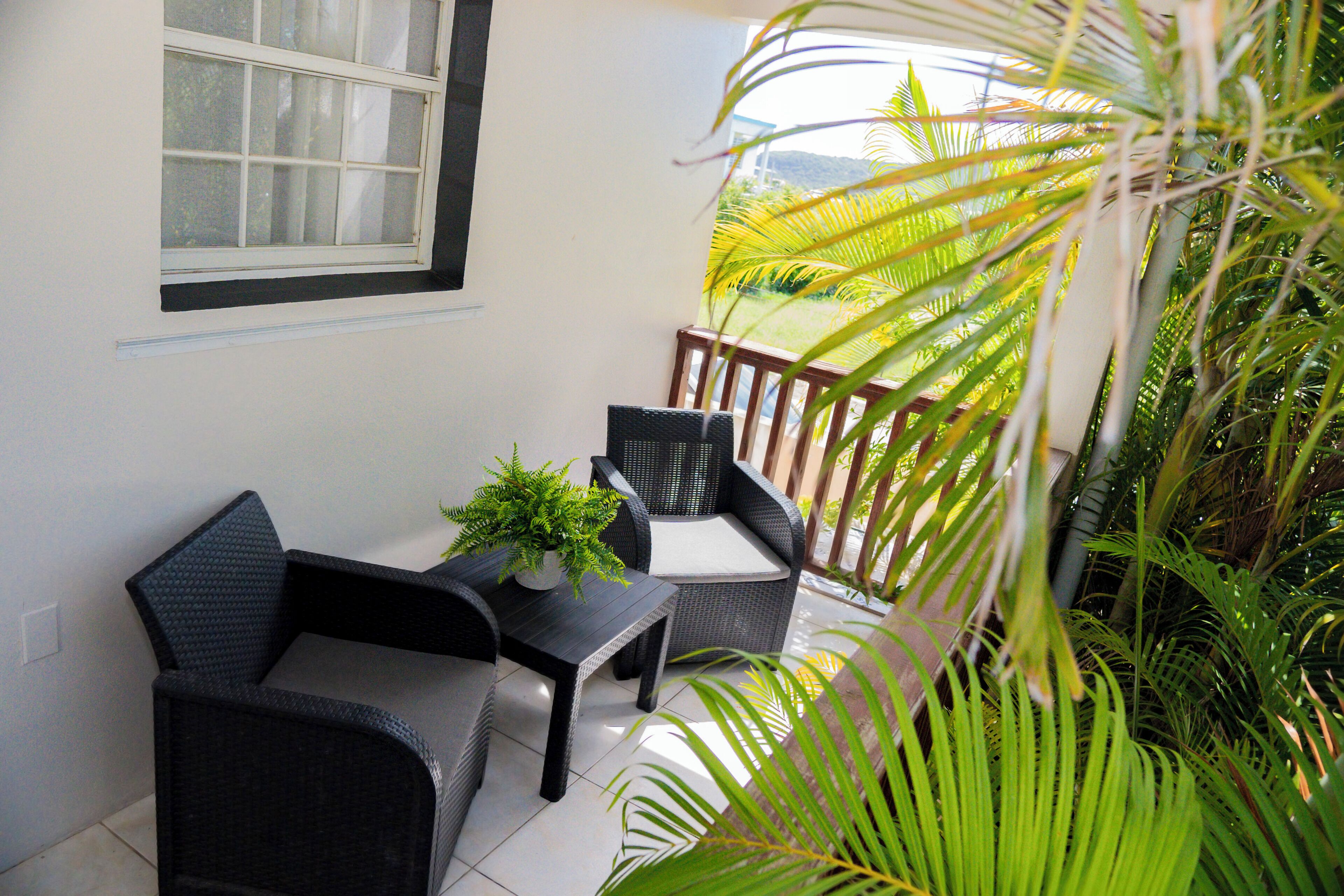 Un balcon avec deux fauteuils en osier, une petite table et une plante en pot.