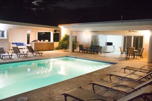 Une piscine avec des chaises longues et un espace extérieur aménagé avec des tables et des chaises.