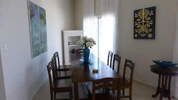 A dining area with a wooden table, chairs, a vase with flowers, and artwork on the walls.