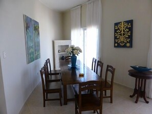 Un coin repas avec une table en bois, des chaises, un vase de fleurs et des œuvres d’art accrochées aux murs.
