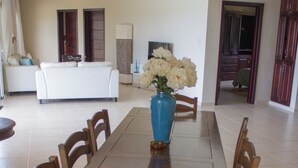 Un comedor con una mesa y sillas de madera, un florero con flores y un ventilador de techo.