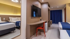 Habitación de hotel con dos camas, un escritorio, una silla, un televisor y un baño.