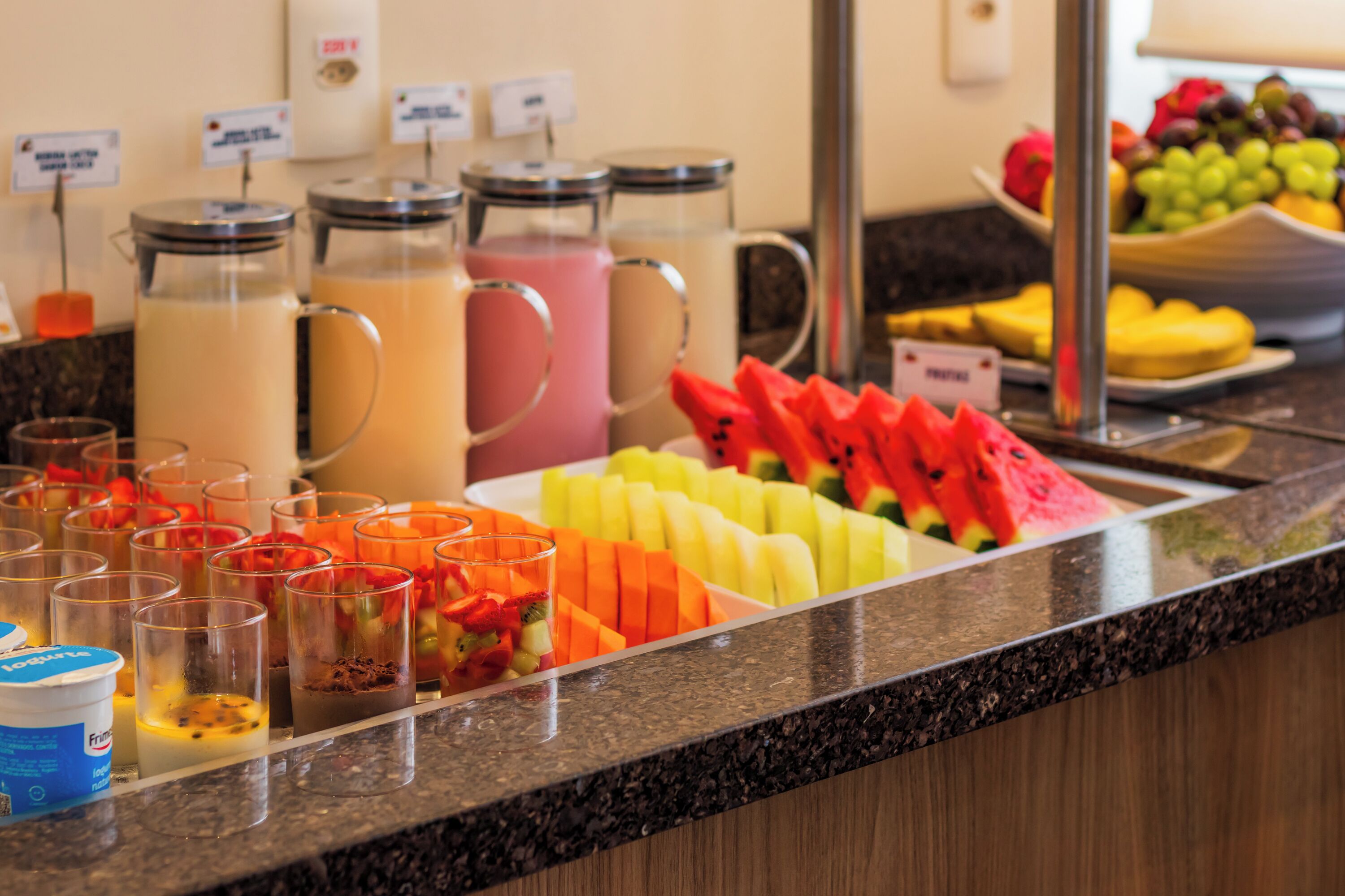 A buffet with various fruit options and beverages.