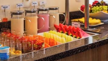 A buffet with various fruit options and beverages.