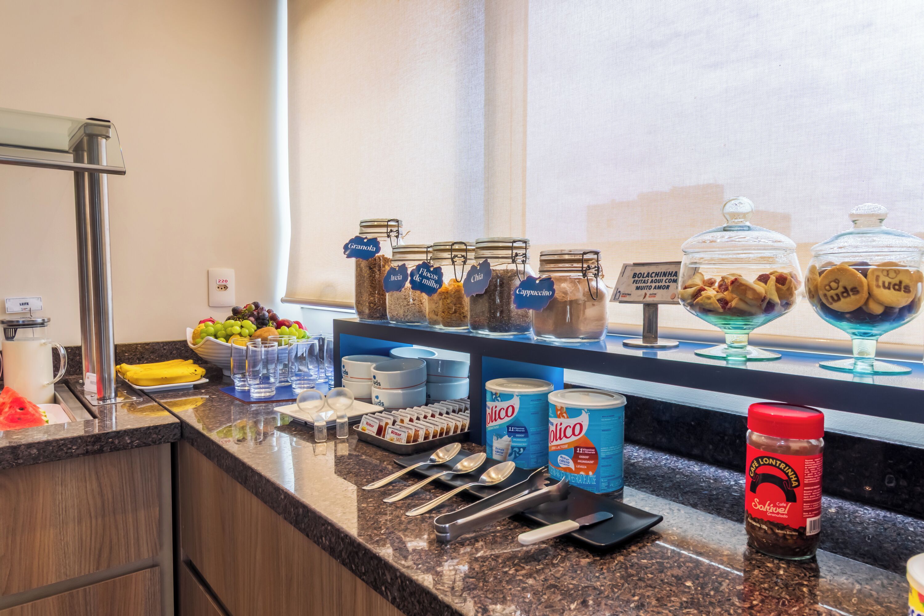A kitchen counter with various food items, jars, and kitchen utensils.