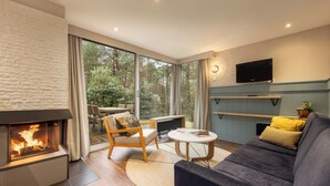 Ein modernes Wohnzimmer mit Kamin, einer Couch, einem Couchtisch und einem an der Wand montierten Fernseher.