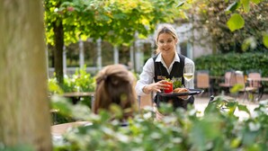 A person serving food at an outdoor table in a garden setting. - Sunparks Kempense Meren (Mol)