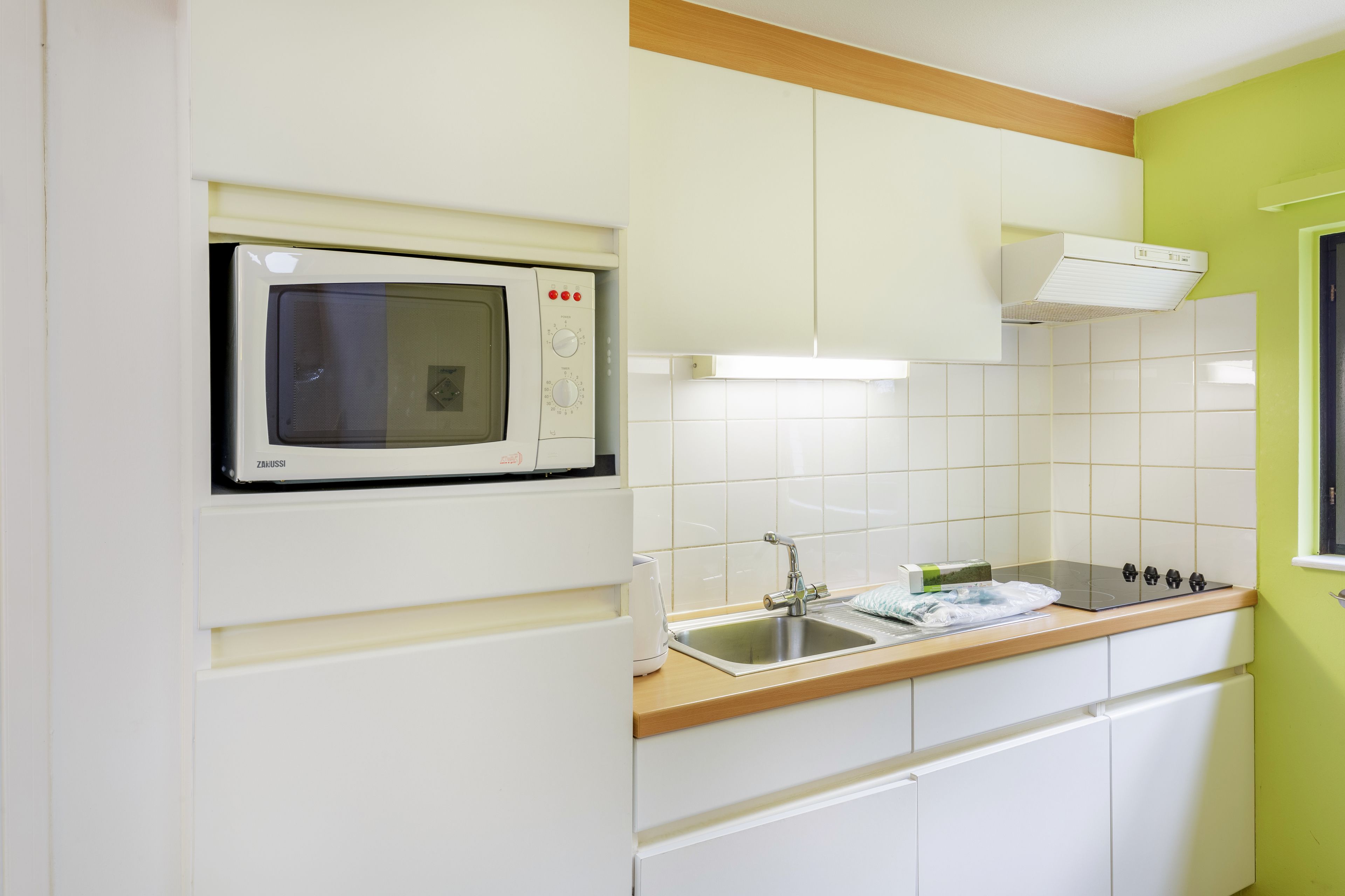 Een keuken met een ingebouwde magnetron, een spoelbak en een fornuis.