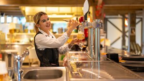A bartender pouring a drink from a tap into a glass. - Sunparks Kempense Meren (Mol)