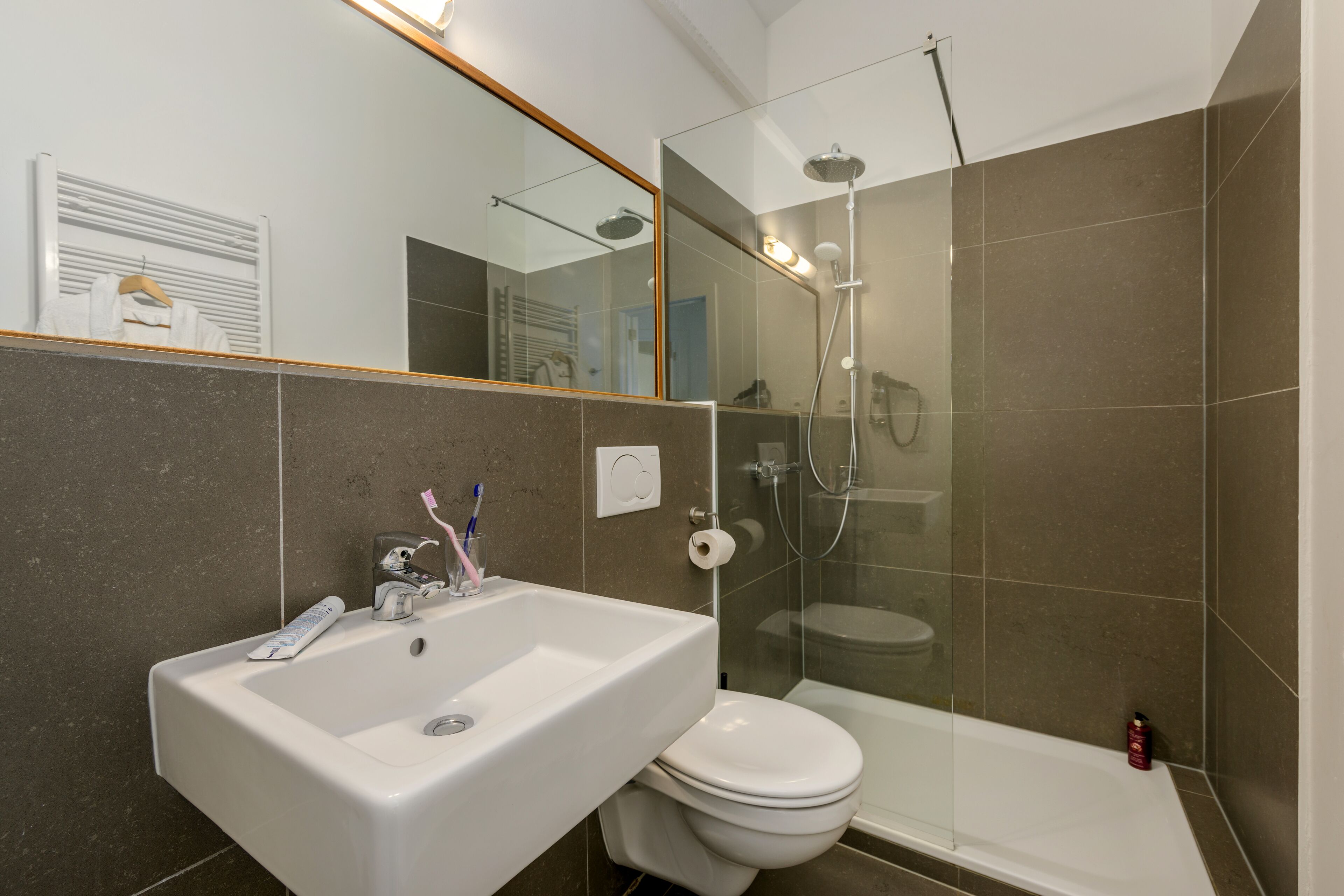 A modern bathroom with a white sink, toilet, and glass-enclosed shower.