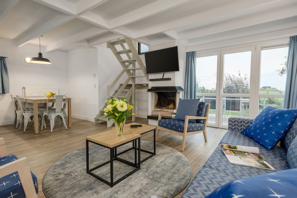 Un salon moderne doté d’un escalier, d’un téléviseur à écran plat, d’une cheminée et d’un balcon offrant une vue agréable.