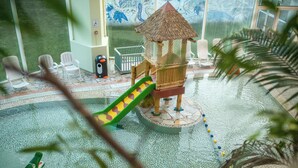 A children's play area with a slide, a small wooden structure, and plastic chairs. - Center Parcs Park de Haan (De Haan)