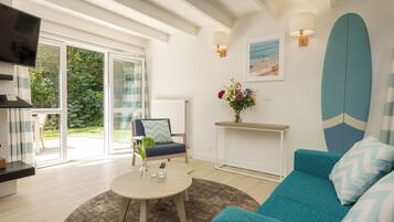 Un salon moderne avec un canapé de couleur turquoise, une table basse ronde et un téléviseur fixé au mur.