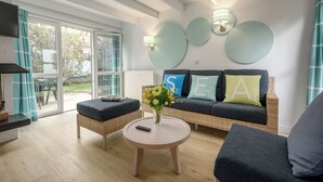 A modern living room with a sofa, two armchairs, a coffee table, and a vase of flowers. - Center Parcs Park de Haan (De Haan)