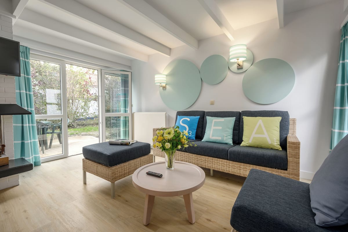 Un salon moderne avec un canapé, deux fauteuils, une table basse et un vase de fleurs.