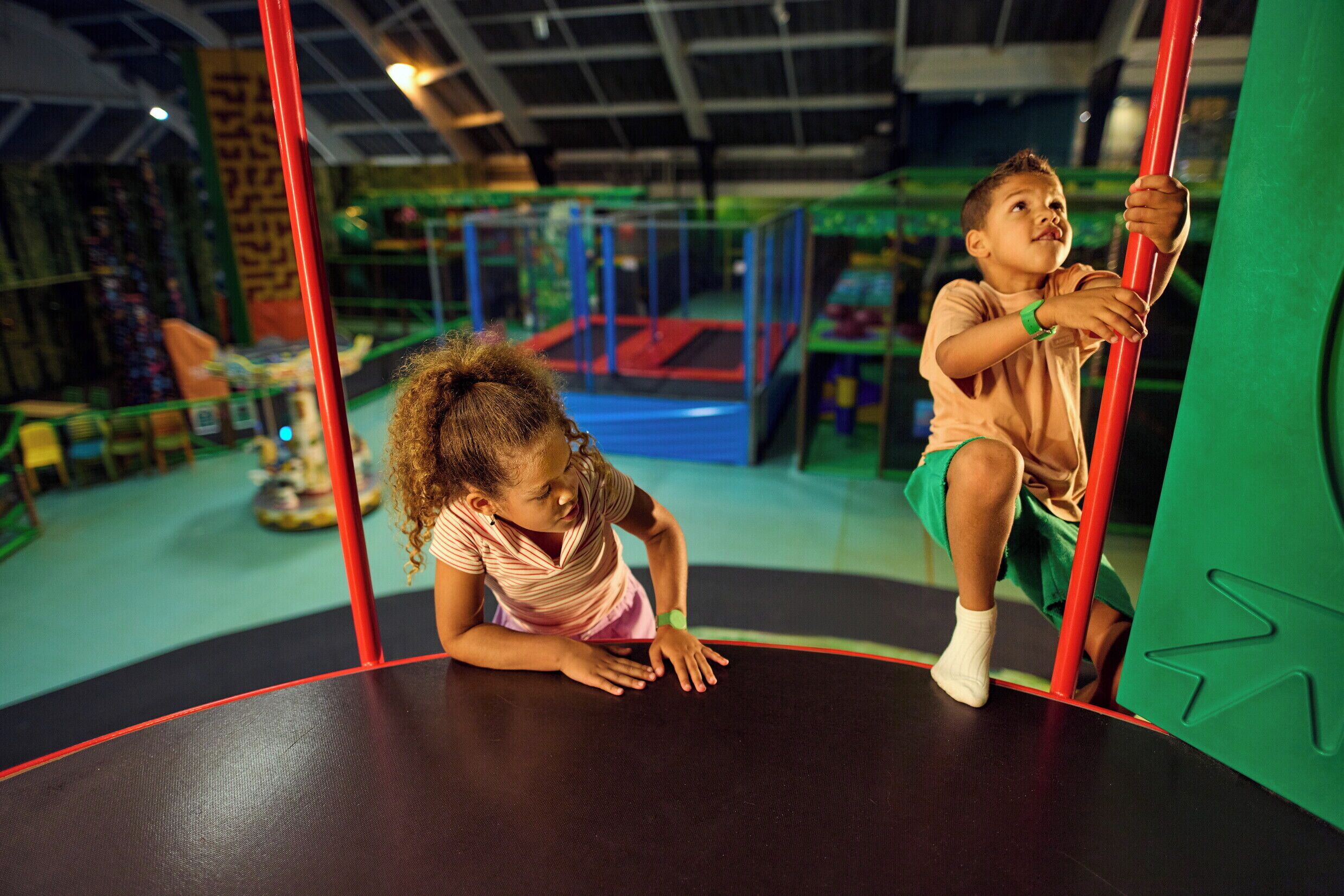 Dos niños jugando en un trampolín con barras de seguridad.