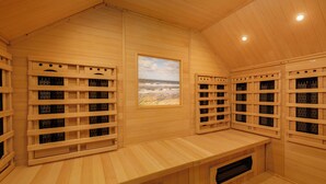 A sauna room with wooden walls, a bench, and a window with a view of the beach. - Center Parcs Park de Haan (De Haan)