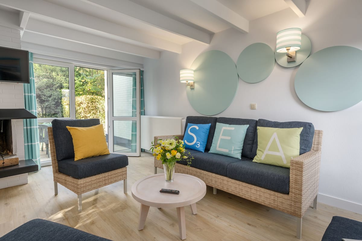 Un salon moderne comprenant un canapé, deux fauteuils, une table basse et une cheminée.