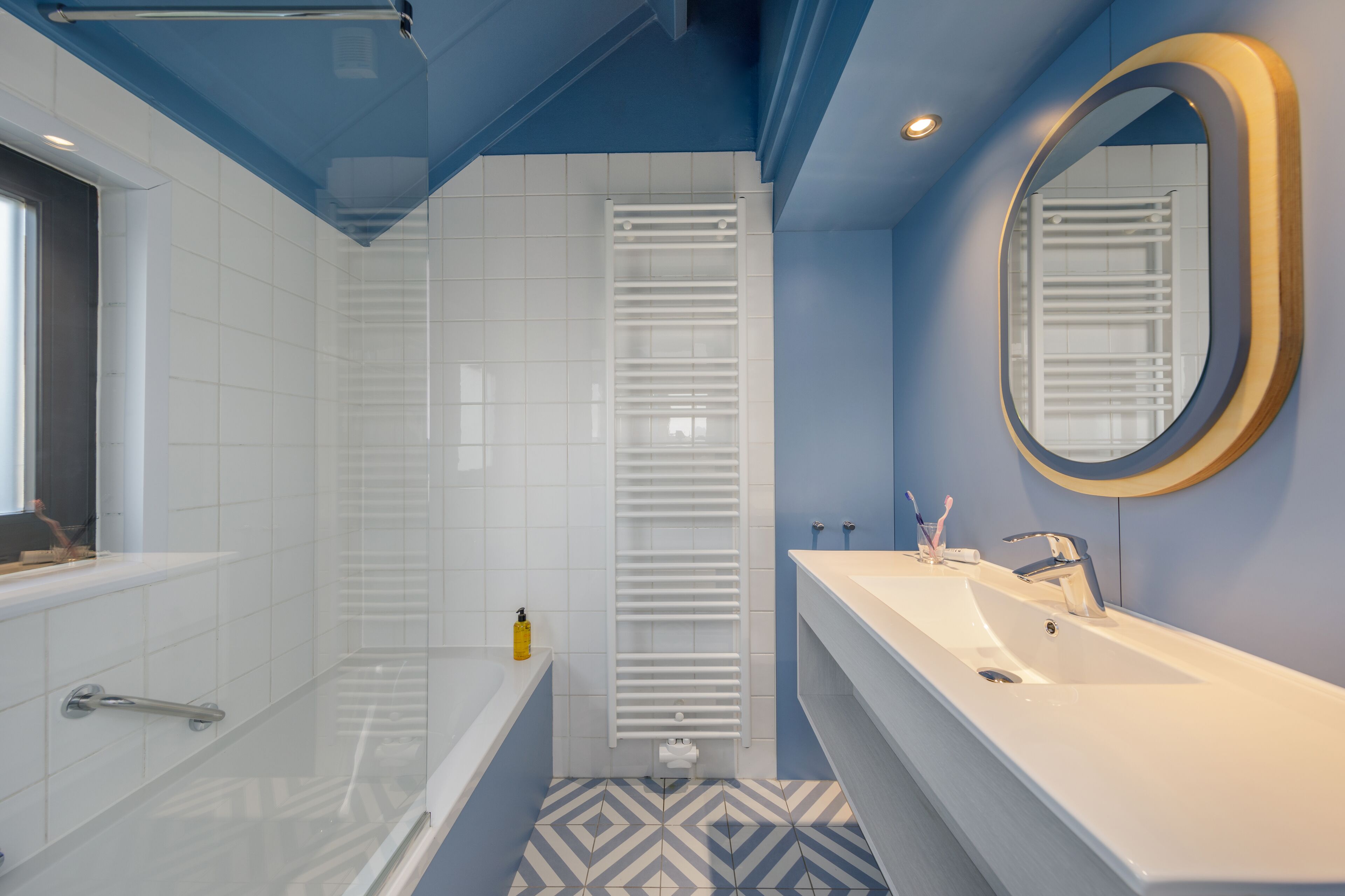 Ein modernes Badezimmer mit Badewanne, Dusche und Waschbecken mit Spiegel.
