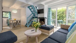 A modern living room with a staircase, a fireplace, and a dining area. - Center Parcs Park de Haan (De Haan)