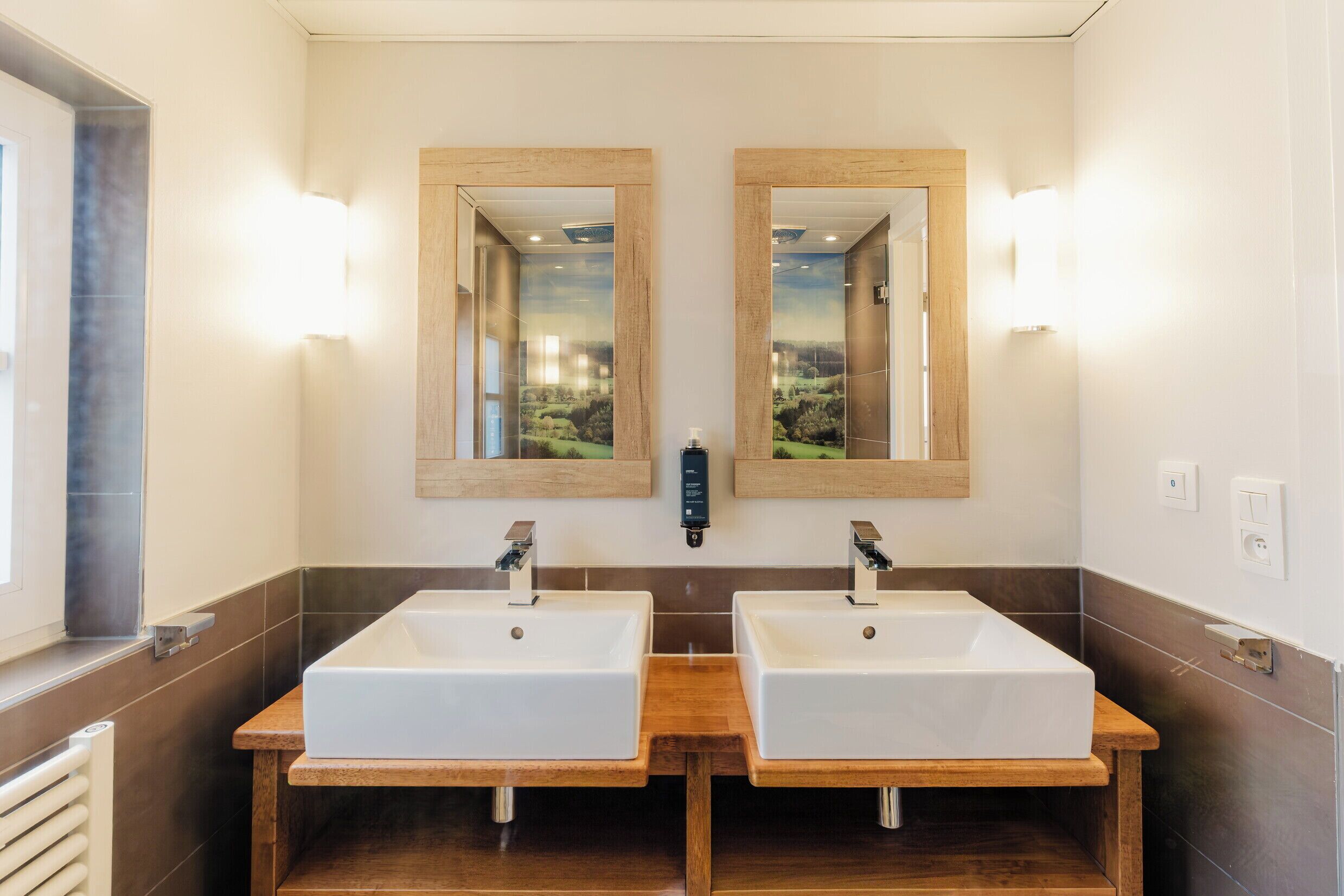 Une salle de bain avec deux lavabos, un meuble-lavabo en bois et des miroirs.