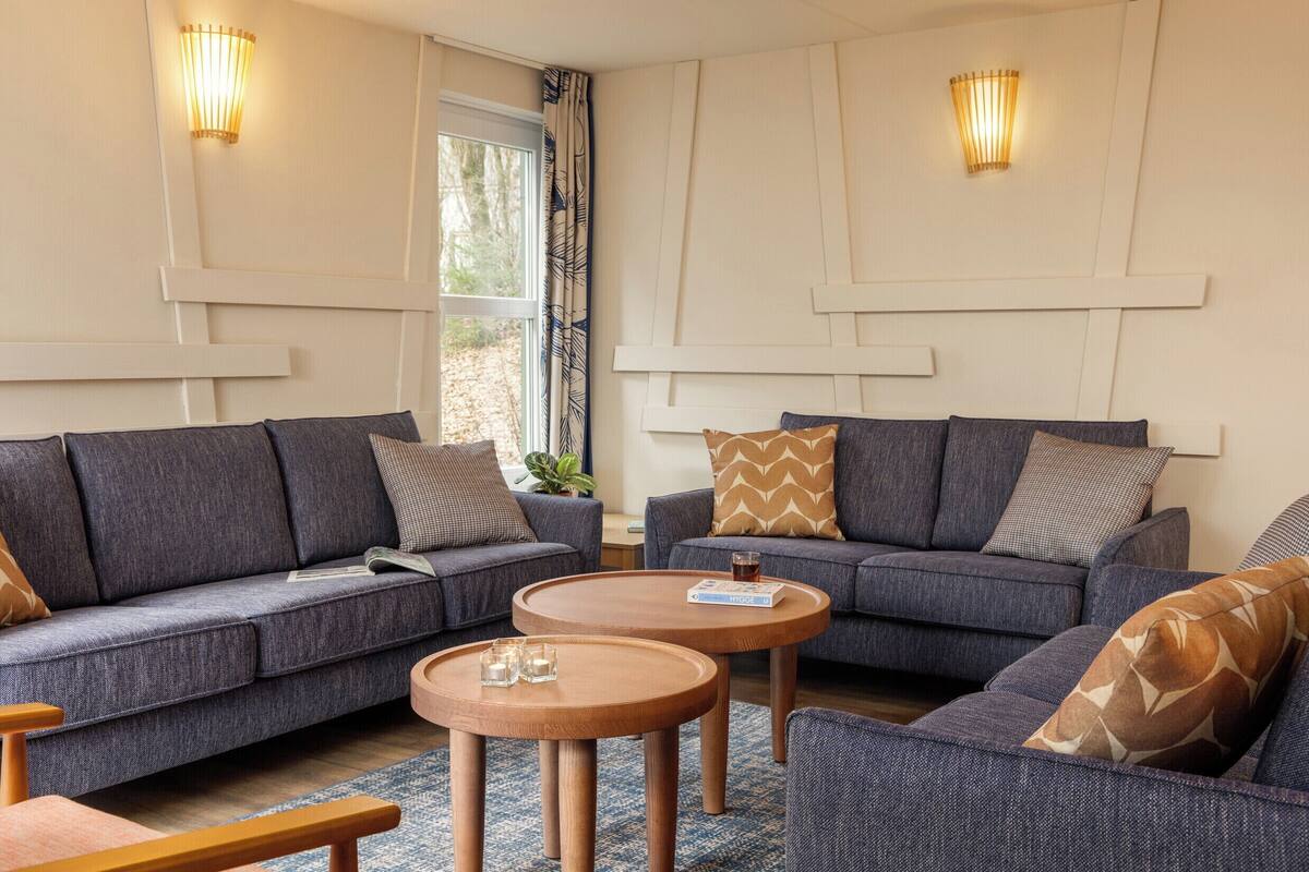 Un salon moderne avec deux canapés, une table basse et des luminaires fixés au mur.