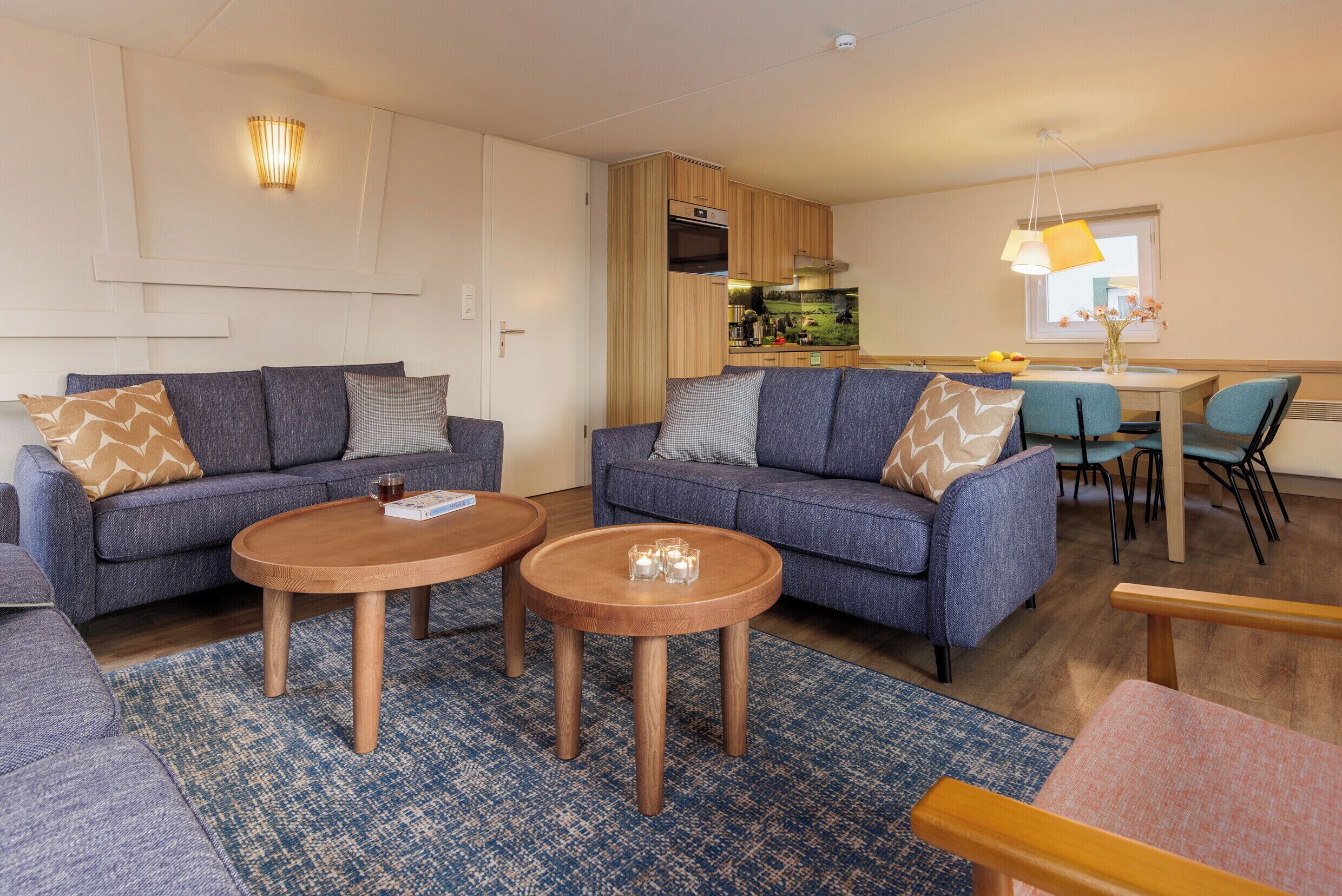 Ein modernes Wohnzimmer mit zwei Sofas, einem Couchtisch und einem Essbereich mit Tisch und Stühlen.