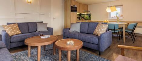 Ein modernes Wohnzimmer mit zwei Sofas, einem Couchtisch und einem Essbereich mit Tisch und Stühlen.