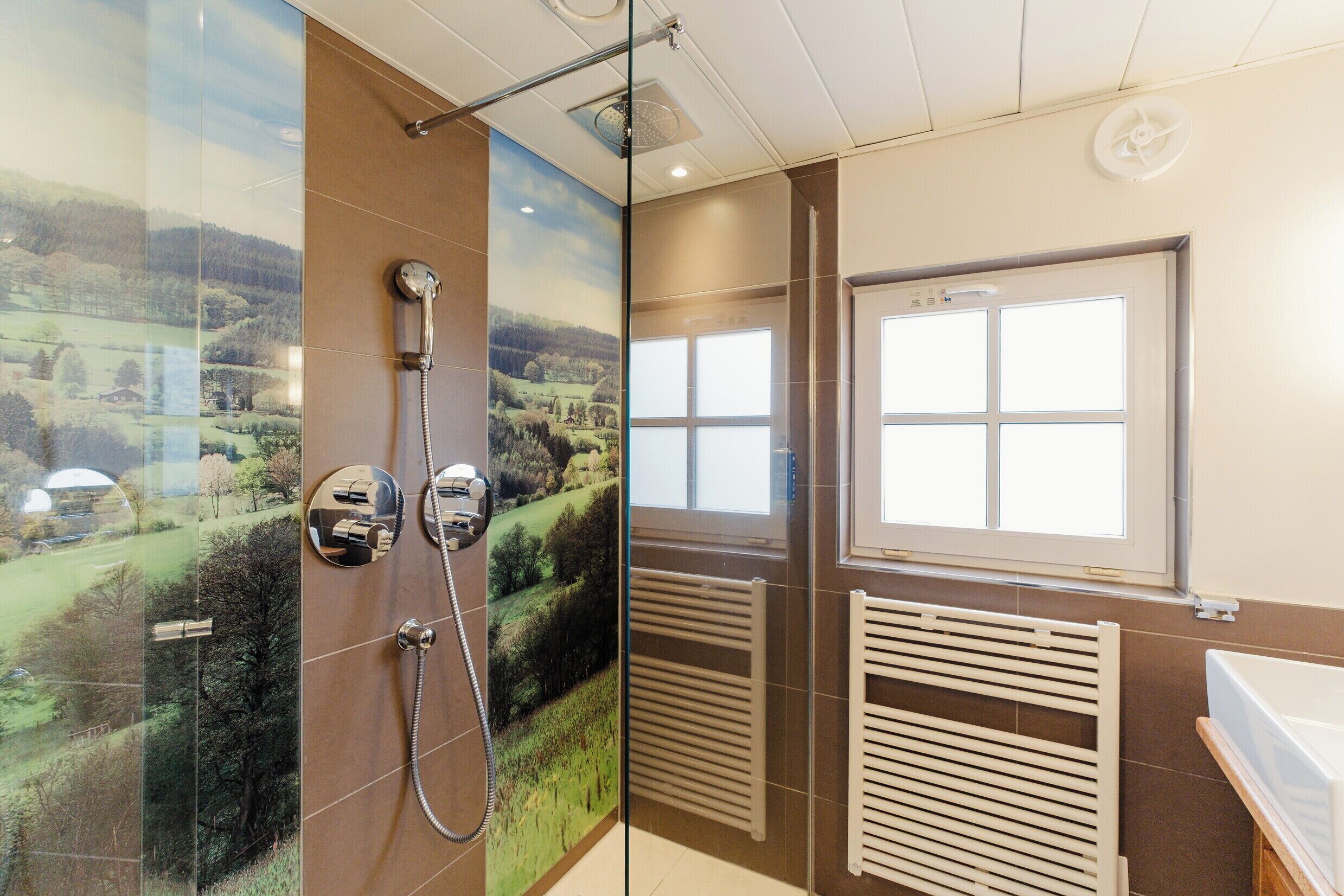 A bathroom with a glass shower enclosure, a window, a radiator, and a bathtub.