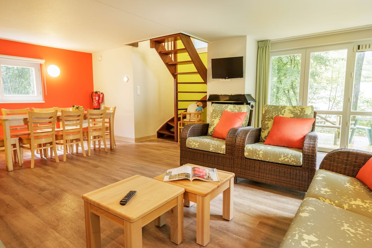 Un salon comprenant un coin repas, un escalier et une grande fenêtre.