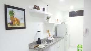 Une cuisine moderne avec des meubles blancs, un plan de travail en granit, un mixeur, une machine à café et un petit îlot central doté d’un évier.