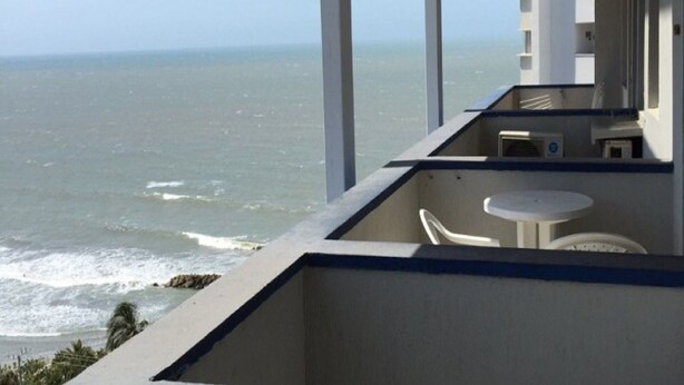 Un balcon avec vue sur l’océan, une petite table et une chaise.