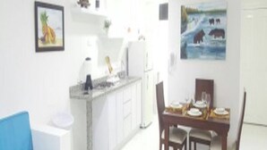 Une cuisine moderne avec des meubles blancs, un canapé bleu et une table à manger avec des chaises.