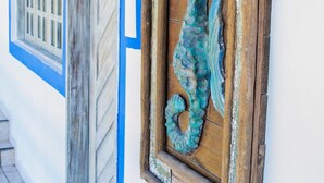 A hallway with a wooden door and a seahorse decoration on the wall. - Pousada Pedra D'Água (Tibau do Sul)
