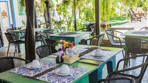 A restaurant with outdoor seating, tables with blue and white patterned tablecloths, and wicker chairs. - Pousada Pedra D'Água (Tibau do Sul)