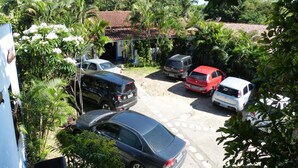 A parking area with several cars, surrounded by lush greenery and palm trees. - Pousada Pedra D'Água (Tibau do Sul)