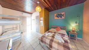 A room with a bed, a wooden bench, a brick wall, and a fish painting. - Pousada Pedra D'Água (Tibau do Sul)