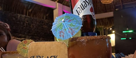 Un verre à cocktail, une tranche de citron vert et une bouteille de bière sont posés sur une table au restaurant The Black Pearl.