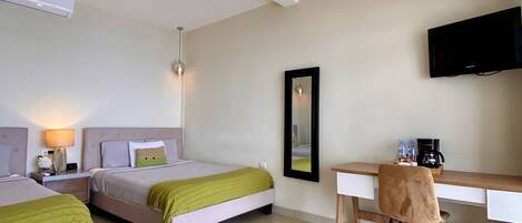 A hotel room with two beds, a desk, a chair, a TV, and a framed picture on the wall.