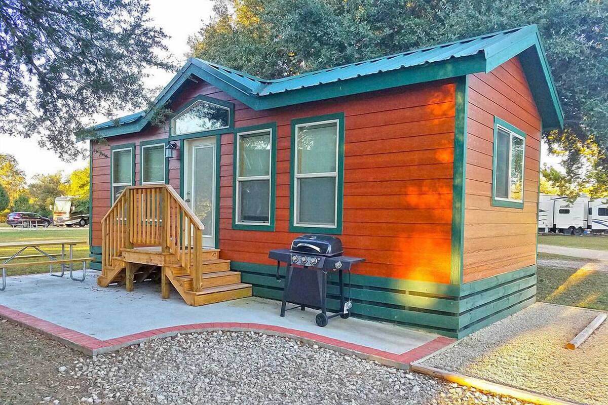 A small, single-story cabin with a porch and a barbecue grill.